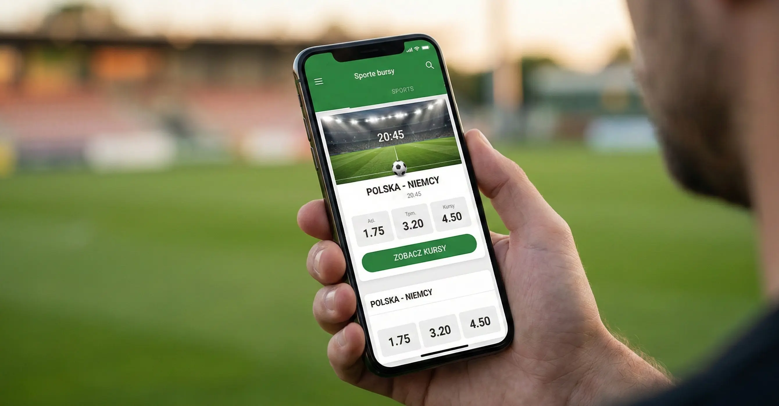 Dłoń trzymająca smartfon z aplikacją bukmacherską na tle stadionu piłkarskiego