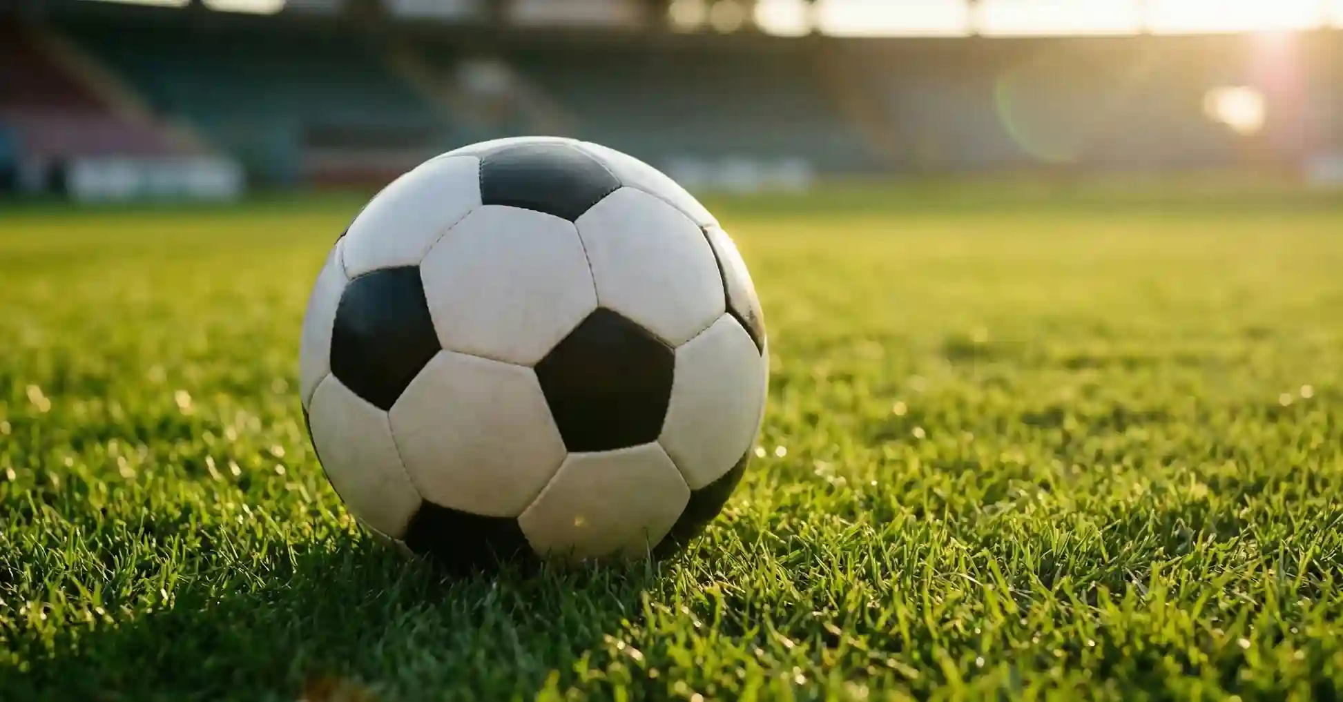 Piłka nożna na murawie stadionu oświetlona promieniami słońca